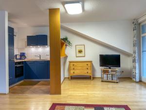 a kitchen with blue cabinets and a flat screen tv at Apartment Juliusruh-4 by Interhome in Juliusruh