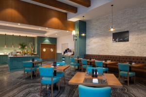 a restaurant with wooden tables and blue chairs at ibis Doha in Doha