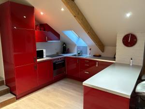 een keuken met rode kasten en witte aanrechtbladen bij Race & Rooms Appartment in Stavelot