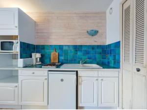 a kitchen with white cabinets and a blue tiled wall at Apartment Port Richelieu 4-2 by Interhome in Cap d'Agde