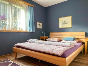 2 camas en un dormitorio con paredes azules y ventana en Apartment Deli by Interhome en Alvaneu