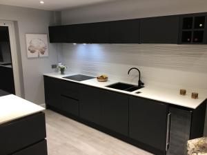 uma cozinha com armários pretos e um lavatório em Redstone Rise Luxury house sleeps 7 em Birkenhead