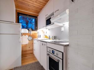 a kitchen with white cabinets and a white refrigerator at Holiday Home Kaltiotievantie 2 mökki 3 by Interhome in Ylläsjärvi