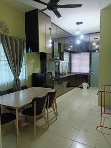 a kitchen and dining room with a wooden table and chairs at Fidaiy Homestay in Teronoh