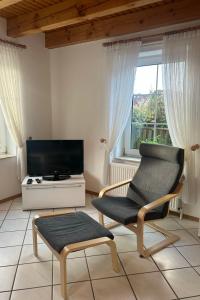a living room with a chair and a tv at Holiday Home Riedehuus by Interhome in Norddeich