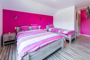 two beds in a bedroom with a pink wall at Le Boca in Les Waleffes