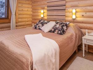 ein Schlafzimmer mit einem Bett in einer Blockhütte in der Unterkunft Holiday Home Tahkon tikka by Interhome in Tahkovuori