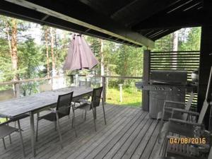 eine Holzterrasse mit einem Tisch, Stühlen und einem Grill in der Unterkunft Holiday Home Villa pinjaranta by Interhome in Tahkovuori