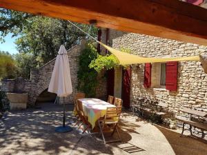 parasol i krzesła oraz stół przed budynkiem w obiekcie Maison de caractère dans Luberon avec piscine w mieście Saignon