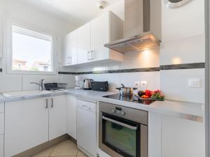 a white kitchen with white cabinets and a sink at Holiday Home Les Lauriers by Interhome in Aigues-Mortes