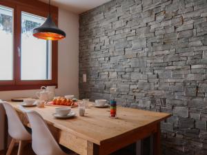 a dining room table with chairs and a brick wall at Apartment Rosablanche E003A by Interhome in Siviez