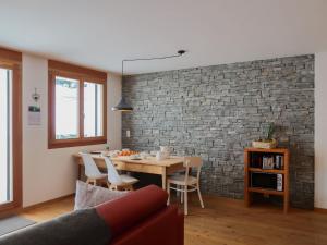 a dining room with a table and a brick wall at Apartment Rosablanche E003A by Interhome in Siviez