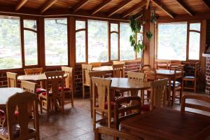 a restaurant with wooden tables and chairs and windows at Hostal Colibri 2 in Baños