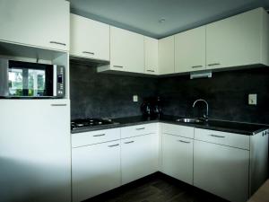 uma cozinha com armários brancos e um lavatório em Holiday Home Duinhoeve-1 by Interhome em Udenhout