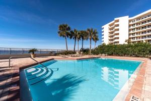 a swimming pool with palm trees and a building at Amazing Waterview Towers 104 Condo With Boat Slip in Destin