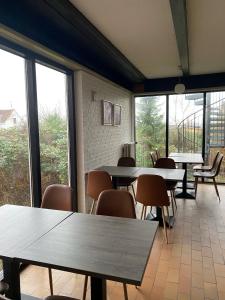 OnlySleep Femern في Holeby: غرفة طعام مع طاولات وكراسي ونوافذ