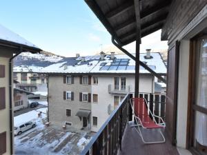 a balcony with a red chair and a snow covered roof at Studio San Anton by Interhome in Bormio