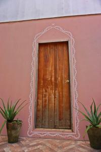 a wooden door in a pink wall with two potted plants at Casa das Irmãs - Só Mulheres - Women Only in Vale do Capao