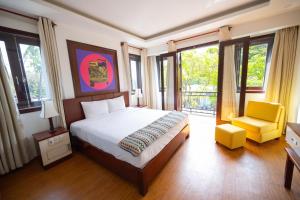 a bedroom with a bed and a chair and windows at Fuse Old Town Hoi An in Hoi An