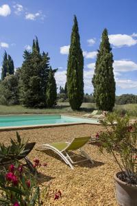 a green lawn chair sitting next to a swimming pool at Chambres d'hôtes Les Baumes in Saint-Quentin-la-Poterie