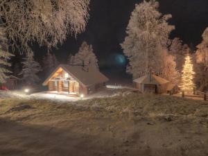 Cabaña de madera con luces en la nieve por la noche en Holiday Home Vanttausranta by Interhome en Oikarainen