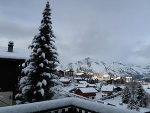 Un árbol de Navidad cubierto de nieve frente a un pueblo en Chalet Ushuaia by Interhome, en Nendaz