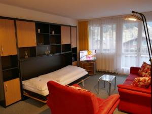 um quarto com uma cama, um sofá e uma televisão em Apartment Chalet Wyssefluh by Interhome em Grindelwald