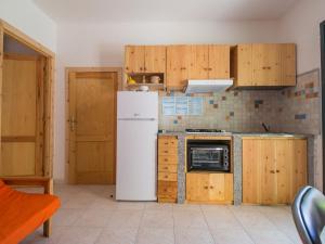 a kitchen with a white refrigerator and wooden cabinets at Apartment Green House by Interhome in La Caletta