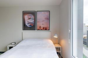 a bedroom with a white bed and three paintings on the wall at Student Factory Le Havre Les Docks in Le Havre