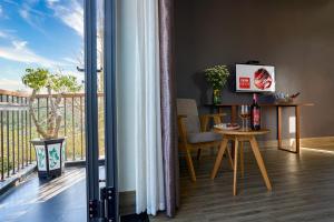 um quarto com uma varanda com uma mesa e uma televisão em An Bang MQ Villa em Hoi An