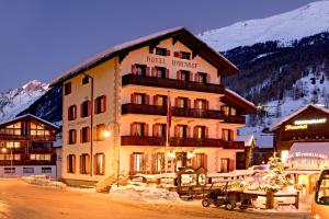 um grande edifício de hotel na neve à noite em Hotel Bahnhof em Zermatt