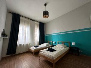 Duas camas num quarto com uma parede azul em Belle Vue Kaiser Apart em Fürth