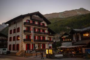 um grande edifício com janelas vermelhas nas montanhas em Hotel Bahnhof em Zermatt