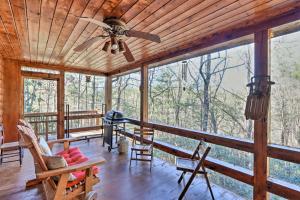 a screened in porch with a ceiling fan and chairs at High Country Cabin with Fire Pit and Hot Tub! in Mineral Bluff