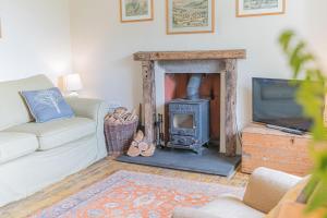 a living room with a fireplace and a tv at Hollin Bank Barn Coniston Water in Coniston