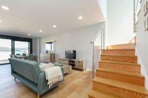 ein Wohnzimmer mit einem blauen Sofa und einer Treppe in der Unterkunft Casa nueva con piscina y vistas al mar in Vilaboa