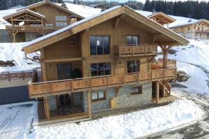 ein großes Holzhaus mit Balkon im Schnee in der Unterkunft Superbe appartement dans luxueux chalet Mt Charvin in Crest-Voland