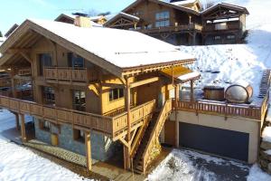 a house with a snow covered roof in the snow at Superbe appartement dans luxueux chalet Mt Charvin in Crest-Voland