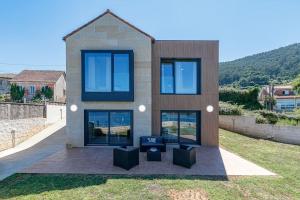 ein Haus mit blauen Fenstern an der Seite in der Unterkunft Casa nueva con piscina y vistas al mar in Vilaboa