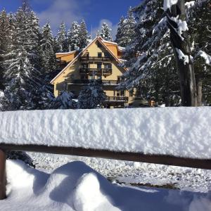 a house covered in snow in front of a fence at Ski apartmány Spiežovec Donovaly in Donovaly