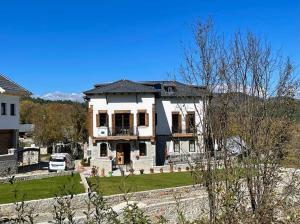 une grande maison blanche avec une voiture garée devant elle dans l'établissement Vila Strugu, à Voskopojë
