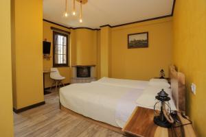 una camera da letto con pareti gialle, un letto e un camino di Vila Strugu a Voskopojë (Moscopoli)