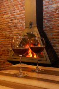 two glasses of wine sitting on a table in front of a fireplace at Vila Strugu in Voskopojë