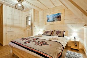 sypialnia z łóżkiem w pokoju z drewnianymi ścianami w obiekcie Domki Baligówka Aurelia i Maximus w Zakopanem