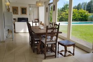 comedor con mesa de madera y sillas en Hermosa casa con fogonero, parrilla cubierta, pileta y jardin parquizado en Benavídez
