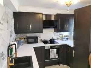 una cocina con armarios negros y encimeras blancas en Stylish and Modern Apartment close to Dover Port! en Kent