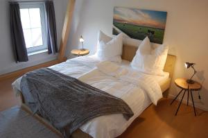 een slaapkamer met een groot bed met witte lakens en kussens bij Ferienwohnung im Gulfhof in Krummhörn