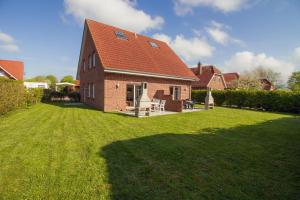 una casa in mattoni rossi con un prato di Haus Leuchtturm - Ebbe a Krummhörn