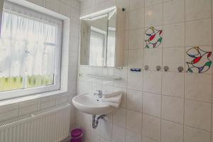 un bagno bianco con lavandino e specchio di Haus Leuchtturm - Ebbe a Krummhörn Altre 15 foto