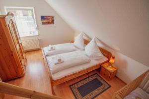 una piccola camera da letto con un letto con lenzuola bianche di Haus Leuchtturm - Ebbe a Krummhörn